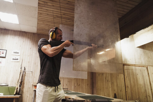 Mann zielt mit einem Gewehr in einer Indoor-Schießanlage - KKAF02590