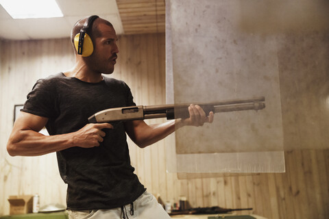 Mann schießt mit einem Gewehr in einer Indoor-Schießanlage, lizenzfreies Stockfoto