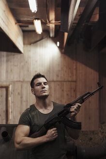 Porträt eines Mannes, der ein Gewehr in einer Schießhalle hält - KKAF02604