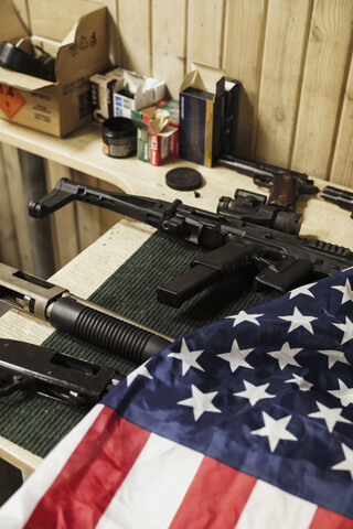 Gewehre, Pistolen und amerikanische Flagge auf dem Tisch, lizenzfreies Stockfoto