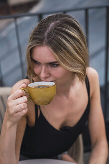 Junge Frau trinkt eine Tasse Kaffee auf der Dachterrasse - KKAF02632