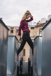 Modische junge Frau auf dem Dach mit kariertem Hemd und schwarzen Jeans - KKAF02659