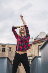 Fashionable young woman wearing plaid shirt on rooftop - KKAF02660