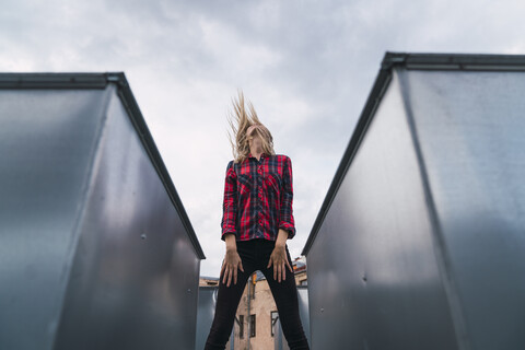 Fashionable young woman on rooftop tossing her hair stock photo