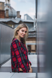 Portrait of smiling blond young woman wearing plaid shirt - KKAF02663