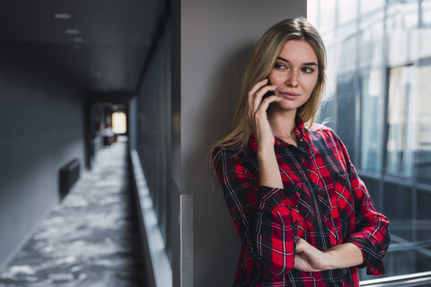 Porträt einer jungen Frau am Telefon in einem modernen Bürogebäude, lizenzfreies Stockfoto