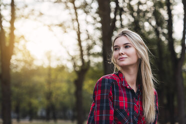 Portrait of young woman wearing plaid shirt in nature - KKAF02671