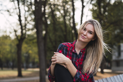 Portrait of blond young woman sitting on bench in autumn stock photo