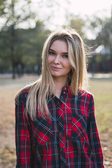 Portrait of blond young woman wearing plaid shirt in autumn - KKAF02683