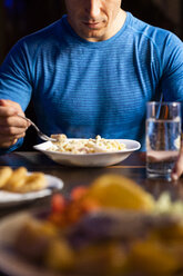 Close-up of athlete eating pasta dish - KKAF02697