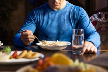 Close-up of athlete eating pasta dish - KKAF02698