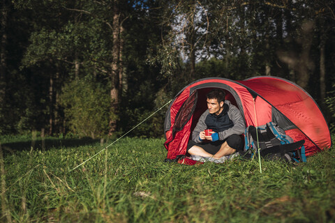 Mann zeltet in Estland, sitzt im Zelt und trinkt Kaffee, lizenzfreies Stockfoto