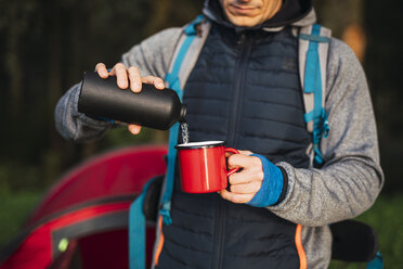 Mann beim Zelten in Estland, gießt Wasser in eine Tasse - KKA02773