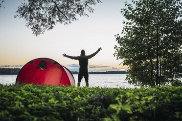 Man camping in Estonia, stretching at lake - KKA02783