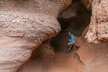 Young man sitting in a cave, looking at map - AFVF01860