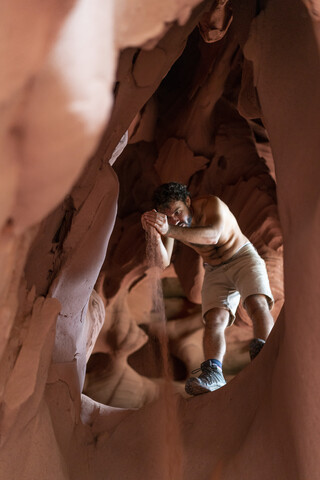 Junger Mann erkundet Höhle, lizenzfreies Stockfoto