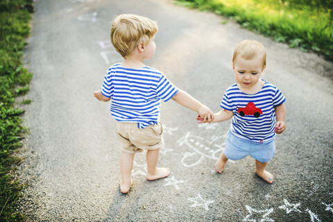 Kleiner Junge spielt mit seiner kleinen Schwester im Freien, lizenzfreies Stockfoto