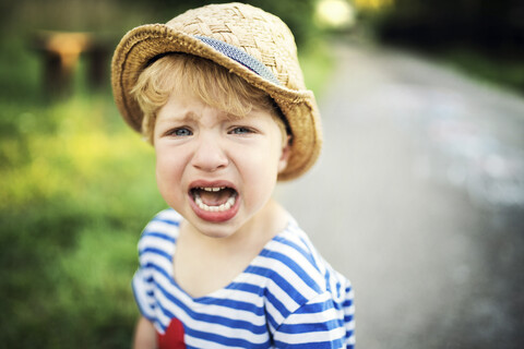 Portrait of screaming toddler wearing straw hat stock photo