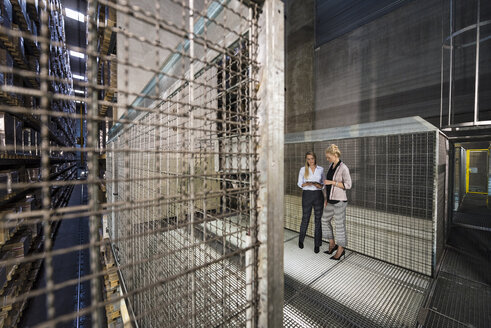 Women using laptop in high rack warehouse - DIGF05420