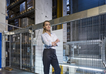 Blond woman in high rack warehouse - DIGF05424