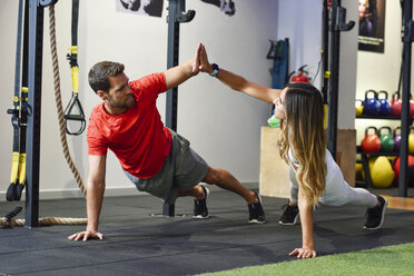 Pärchen bei der Übung Side Plank mit High-Five in einer Turnhalle - JSMF00488