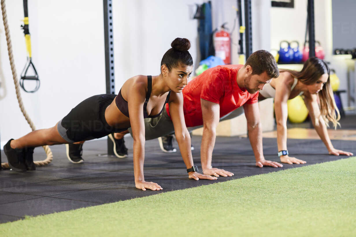 Young people exercising plank variations in a gym stock photo