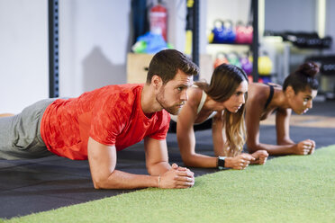 Junge Leute beim Üben von Plank-Variationen in einem Fitnessstudio - JSMF00491