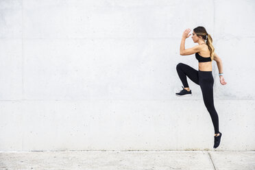 Athlete jumping in front of white wall - JSMF00509