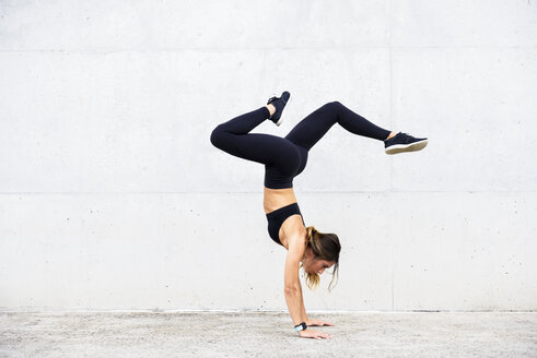 Athlete doing handstand in front of white wall - JSMF00510