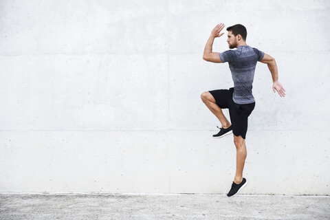 Sportler springt vor einer weißen Wand, lizenzfreies Stockfoto