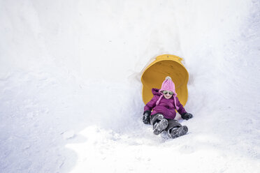 Cute girl wearing sunglasses while playing with sled on snow covered field - CAVF50619