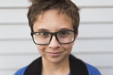 Close-up portrait of boy wearing eyeglasses while standing by wall - CAVF50652
