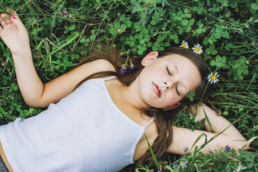 High angle view of girl sleeping on field amidst plants at park - CAVF50653