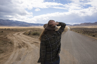 Rear view of woman wearing hat while standing on road against cloudy sky at Bryce Canyon National Park - CAVF50742