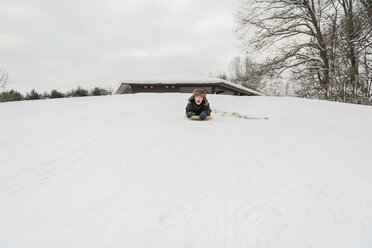 Verspielter Junge schreit beim Schlittenfahren im Schnee im Winter - CAVF50763