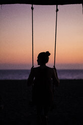 Rückansicht der Silhouette Frau schwingt am Strand gegen den Himmel bei Sonnenuntergang - CAVF50772