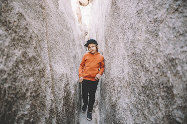 Porträt eines Jungen, der bei Felsformationen im Joshua Tree National Park steht - CAVF50778