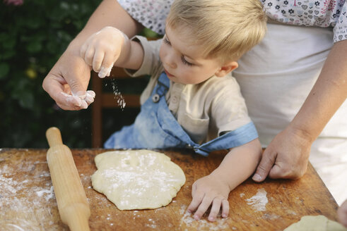 Mittelteil einer Mutter mit ihrem Sohn, die auf einem Holztisch im Hof Essen zubereitet - CAVF50826