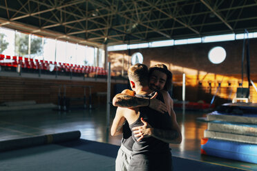 Happy friends embracing while standing at gym - CAVF50853