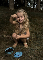 Verspieltes Mädchen, das ein Insekt hält, während es im Wald hockt - CAVF50860