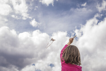 Rückansicht eines Mädchens, das einen Drachen gegen einen bewölkten Himmel steigen lässt - CAVF50866