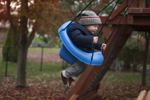 Voller Länge von Baby Junge schwingt auf Schaukel im Park, lizenzfreies Stockfoto
