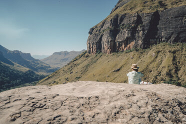 Rückansicht einer auf einem Berg sitzenden Frau an einem sonnigen Tag - CAVF50884