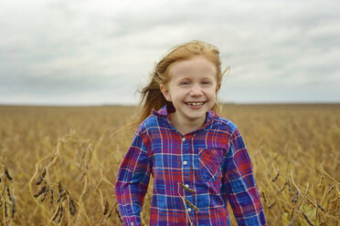 Porträt eines fröhlichen Mädchens inmitten eines Sojabohnenfelds gegen den Himmel - CAVF50901