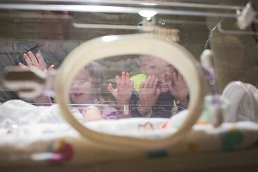 Niedriger Blickwinkel von Geschwistern, die ihren neugeborenen Bruder im Krankenhaus betrachten - CAVF50903