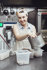 Porträt einer fröhlichen Frau, die in einer Großküche Eiscreme herstellt - CAVF50909