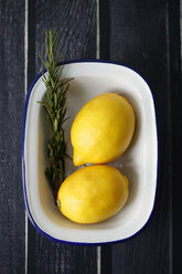 Blick von oben auf Zitronen mit Rosmarin in einer Schale auf einem Holztisch - CAVF50920