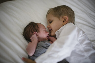 High angle view of boy lying by newborn brother on bed at home - CAVF50982