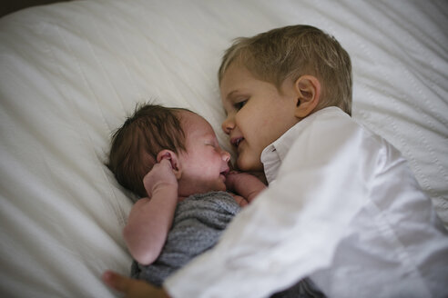 Hoher Blickwinkel des Jungen, der neben seinem neugeborenen Bruder auf dem Bett zu Hause liegt - CAVF50982