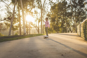 Side view of boy skateboarding on footpath at park during sunset - CAVF50990